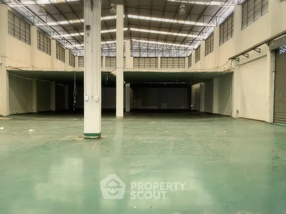 Spacious industrial warehouse with high ceilings and ample natural light, perfect for storage or manufacturing.