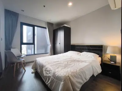 Modern bedroom with large window and stylish furnishings in a contemporary apartment.