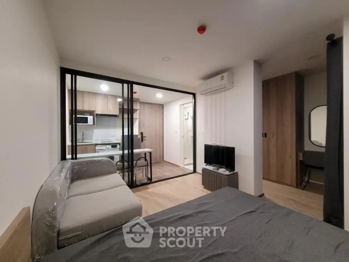 Modern studio apartment with open kitchen and cozy living area, featuring sleek furniture and contemporary design.