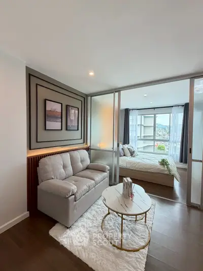 Modern living room with cozy sofa and stylish decor leading to a bright bedroom with scenic view.