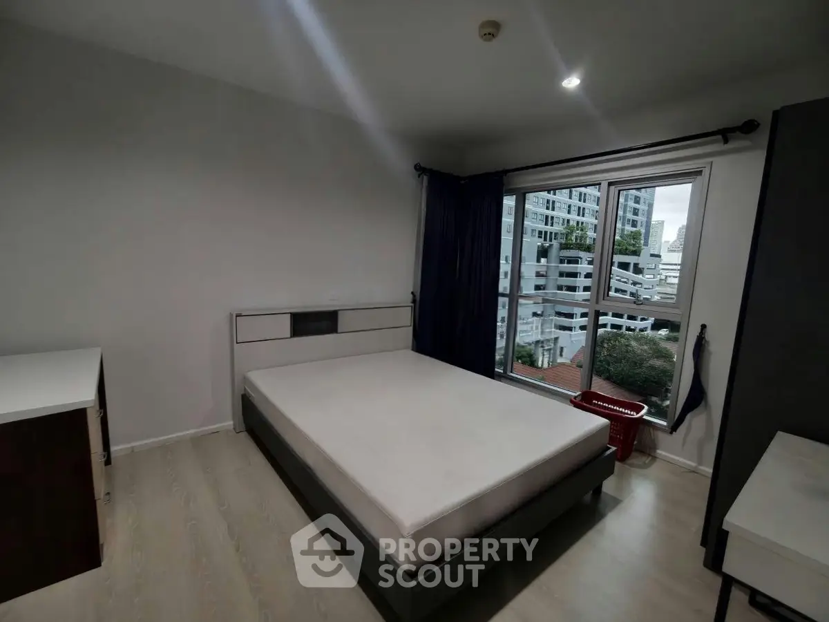 Spacious bedroom with large window offering city view in modern apartment