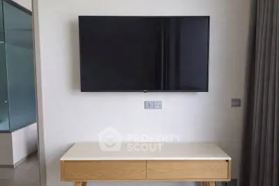 Modern living room with wall-mounted TV and stylish wooden console table.