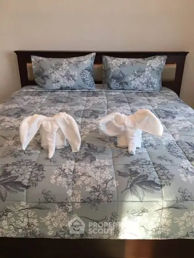 Elegant bedroom with floral bedding and towel art elephants on bed, creating a welcoming atmosphere.