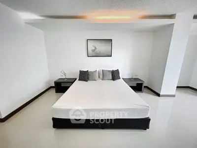 Spacious minimalist bedroom with modern decor and ample natural light.
