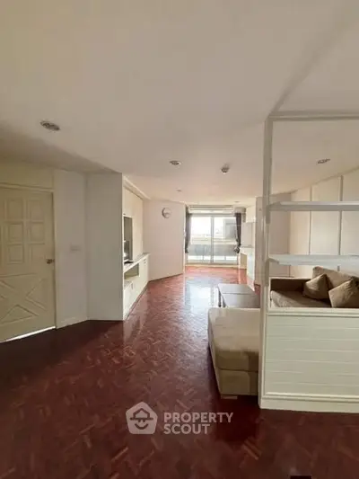 Spacious living room with elegant parquet flooring and cozy seating area, featuring natural light from large windows.
