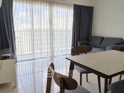 Bright living room with large windows and modern furniture in a high-rise apartment.