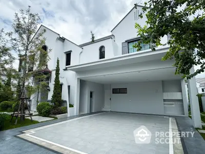 Modern white exterior house with spacious driveway and lush greenery