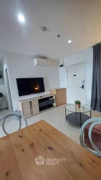 Modern living room with sleek furniture and wall-mounted TV in a cozy apartment.