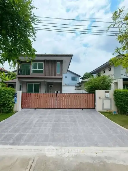 Modern two-story house with spacious driveway and wooden gate in a suburban neighborhood.