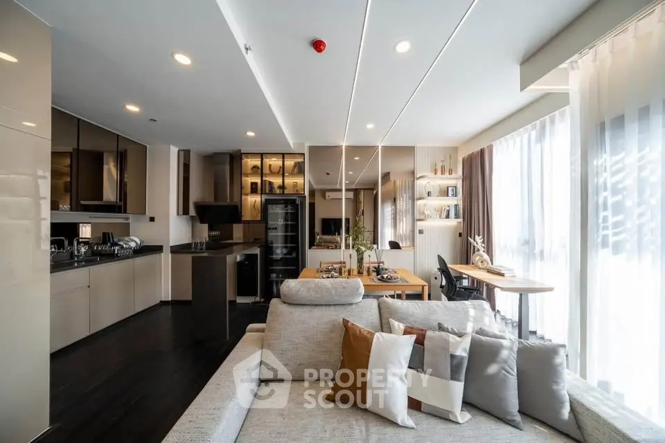 Spacious modern living room with open kitchen and dining area, featuring elegant decor and ample natural light.