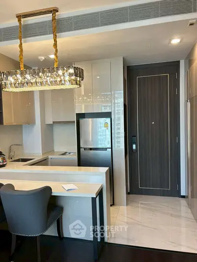 Luxurious modern kitchen with elegant chandelier and sleek cabinetry in high-end apartment.