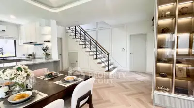 Elegant open-plan living area with modern kitchen and stylish staircase in a bright, airy home.