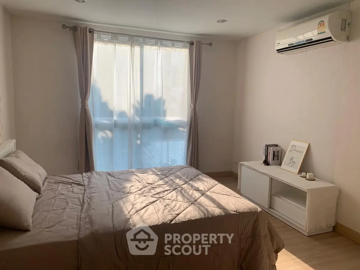 Cozy bedroom with natural light, featuring a comfortable bed and modern air conditioning unit.