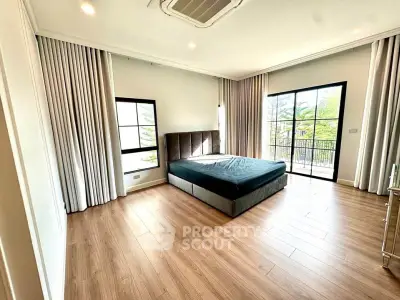 Spacious bedroom with large windows and balcony access in modern apartment