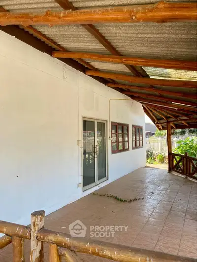 Charming rustic patio with wooden beams and garden view, perfect for relaxation.