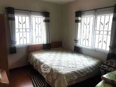 Cozy bedroom with natural light and stylish window grills, perfect for relaxation.