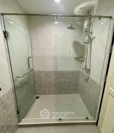 Modern bathroom with glass shower enclosure and sleek tile design.
