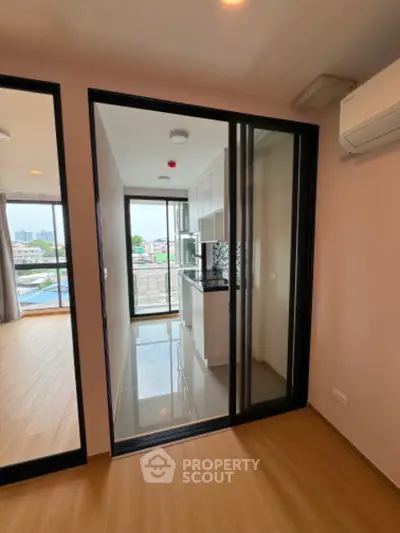 Modern apartment with sleek kitchen and balcony view, featuring open layout and air conditioning.