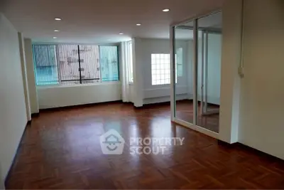 Spacious empty room with wooden flooring and large windows