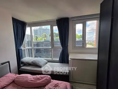 Cozy bedroom with large windows offering city views and natural light.