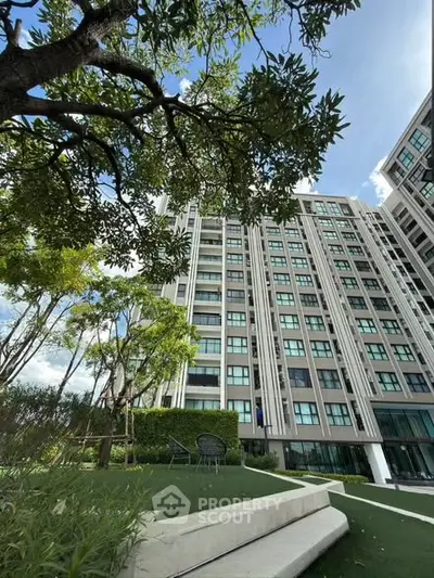 Modern high-rise building with lush garden and clear blue sky, perfect for urban living.