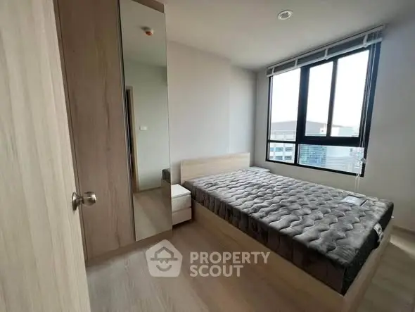 Modern bedroom with large window and wooden furniture in urban apartment