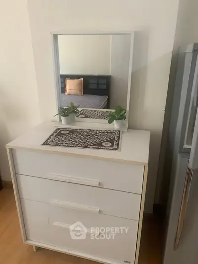 Modern bedroom with stylish dresser and mirror, featuring a cozy bed and elegant decor.