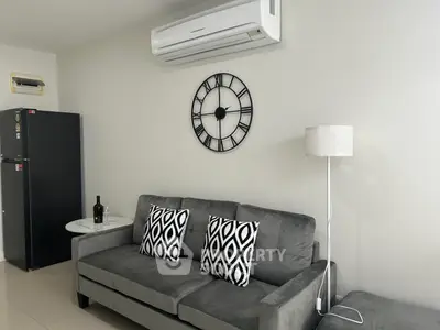 Modern living room with stylish grey sofa, geometric cushions, and wall-mounted air conditioner.