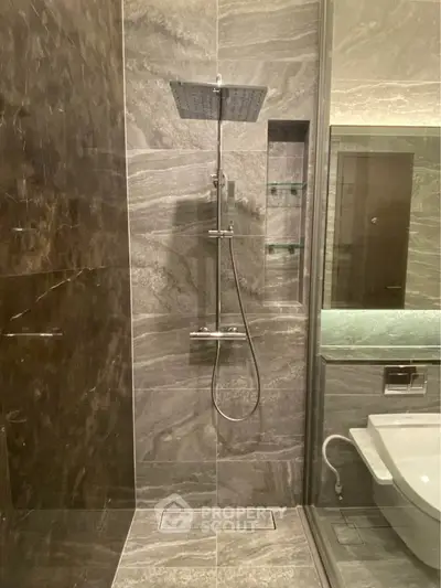 Luxurious modern bathroom with sleek marble tiles and a rainfall showerhead, perfect for a spa-like experience.
