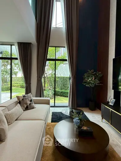 Luxurious high-ceiling living room with large windows and elegant decor