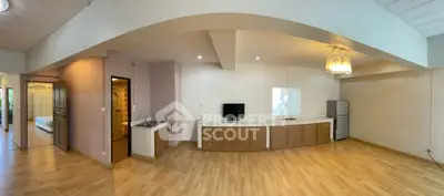 Spacious open-plan living area with modern kitchenette and wooden flooring