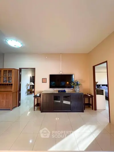 Spacious living room with modern TV setup and elegant furniture, perfect for relaxation and entertainment.