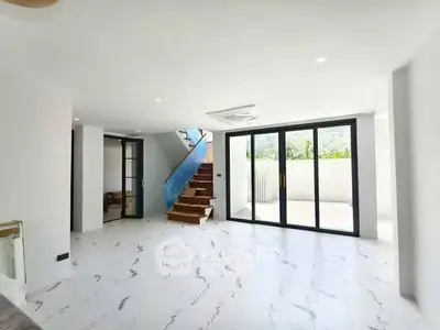 Spacious modern living room with marble flooring and large glass doors leading to a balcony.