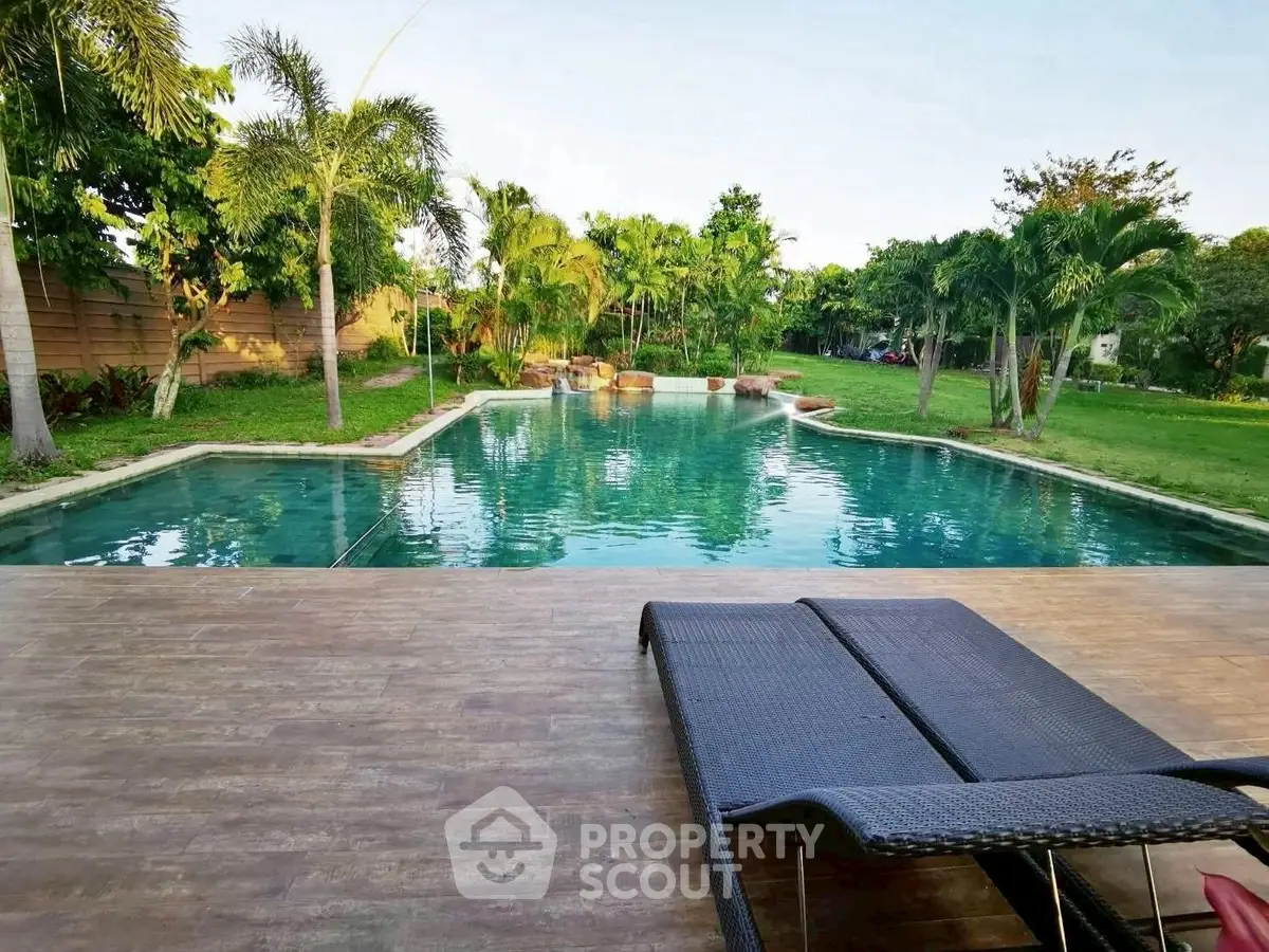 Luxurious outdoor pool with lush greenery and relaxing sun loungers.