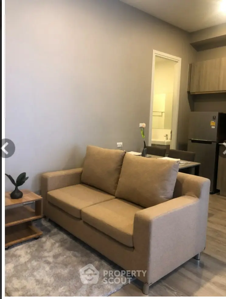Cozy living room with beige sofa and modern kitchen area