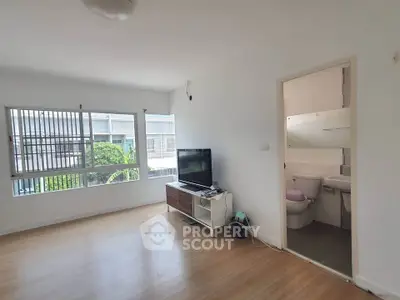 Spacious living room with natural light and adjacent bathroom in modern apartment.
