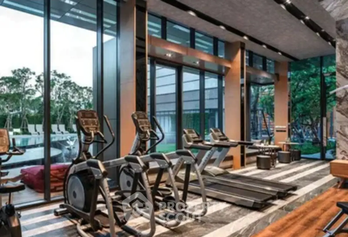 Luxurious gym with modern equipment and pool view in upscale residential complex.