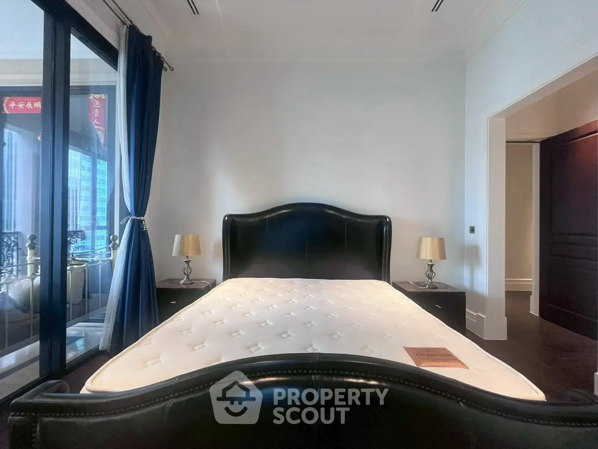 Luxurious bedroom with elegant black leather bed and city view balcony.