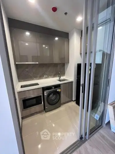 Modern compact kitchen with sleek cabinetry and built-in appliances in a stylish apartment.