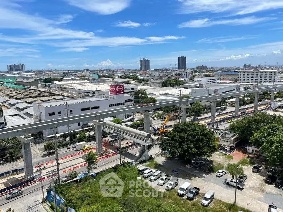 Panoramic cityscape view with construction site and urban skyline under a clear blue sky.