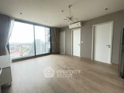 Spacious modern living room with large windows and city view, featuring sleek flooring and elegant lighting.
