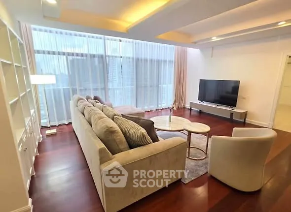 Spacious living room with modern furniture and large windows offering city views.