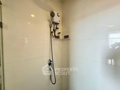 Modern bathroom shower area with sleek white tiles and mounted showerhead