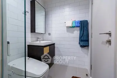 Modern bathroom with sleek design and white subway tiles, featuring a stylish vanity and toilet.