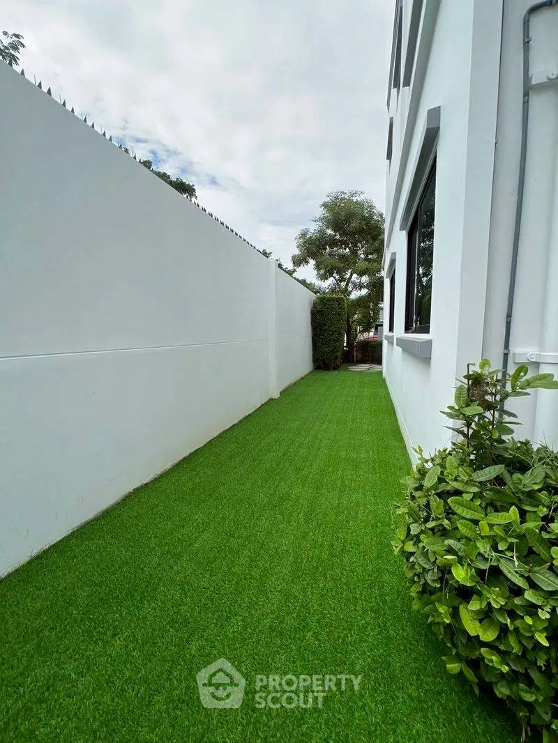 Modern side garden with lush artificial grass and sleek white walls
