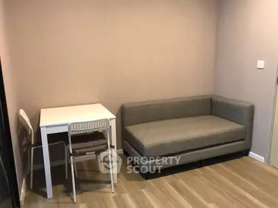 Cozy living room with modern gray sofa and compact dining table set on wooden flooring.