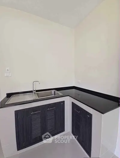 Modern kitchen with sleek black countertops and dual sink in a compact corner layout.
