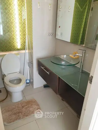 Modern bathroom with glass sink and stylish green accent wall