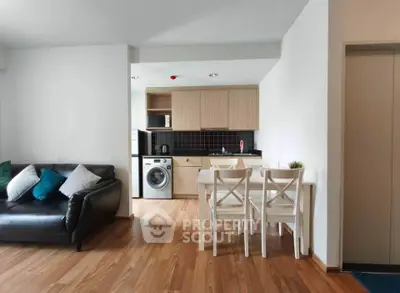 Modern open-plan living room with kitchen featuring wooden flooring and sleek furniture.