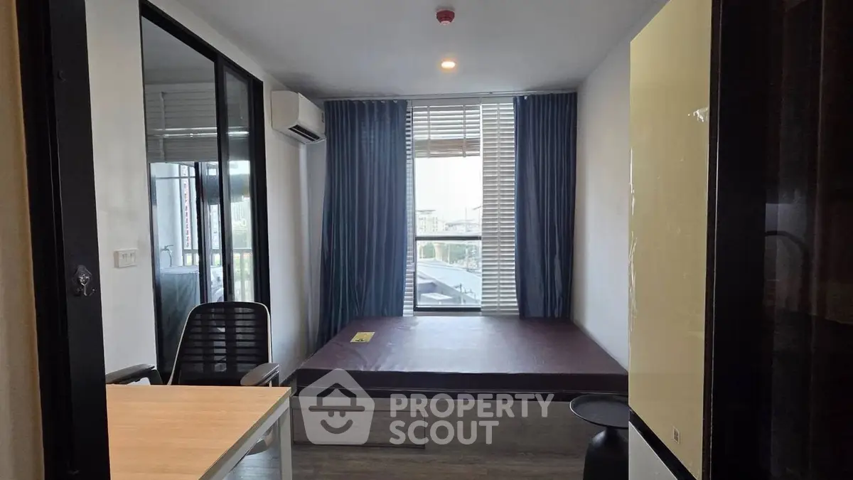 Modern compact bedroom with large window and built-in bed, featuring sleek design and natural light.